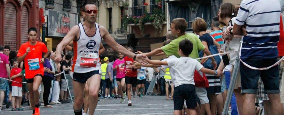 在潘普洛纳的圣费尔明马拉松期间，赛跑者向观众挥手。
