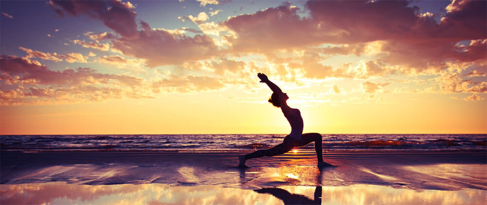 日落时在海滩上练习瑜伽的女子